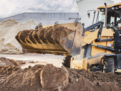 The excavator loader works with a bucket for transporting sand at a construction site. Professional construction equipment for earthworks